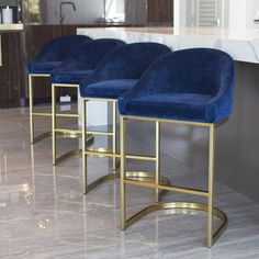 three blue velvet bar stools sitting on top of a marble counter