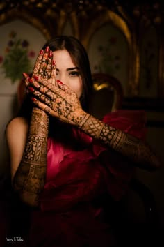 a woman holding her hands up to her face with henna on top of her