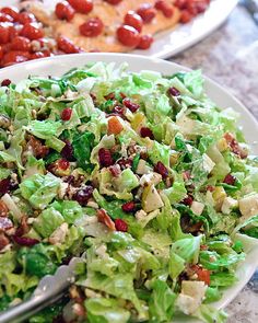 a white plate topped with lettuce and cranberries next to other foods