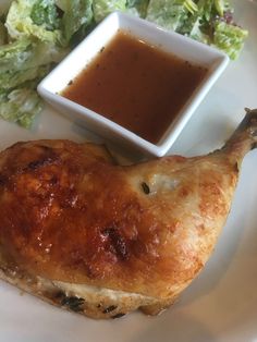 a white plate topped with chicken wings next to a small bowl of sauce and lettuce