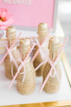 small corks are tied to the top of wine bottles with pink ribbons on them