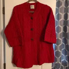 a red cardigan sweater hanging on a door