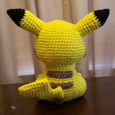 a knitted pikachu sitting on top of a wooden table