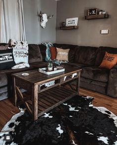 a living room filled with furniture and cow skin rugs on the floor in front of a brown couch