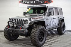 a gray jeep is parked in front of a sign that says rubitox on it