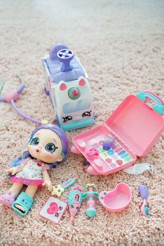 there is a doll and other toys laying on the floor in front of a suitcase