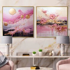 two pink chairs and a table in a room with paintings on the wall behind them