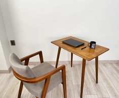 two chairs and a table with a laptop on it in front of a white wall