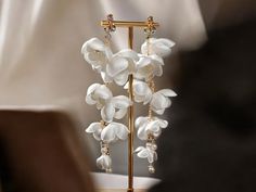 a pair of earrings with white flowers hanging from it's ear posts on a stand