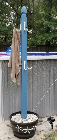 a potted plant sitting next to a pool with a towel hanging from it's pole