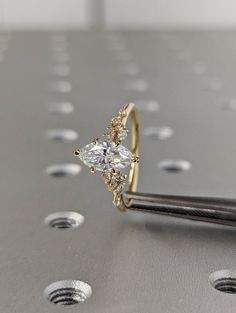 a close up of a diamond ring on top of a piece of metal with holes in the background