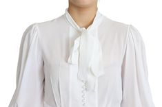 Exude sophistication with this pristine Dolce & Gabbana snow-white blouse, perfect for elevating your wardrobe. Crafted in Italy, this stunning piece showcases an ascot collar and long lantern sleeves. The fitted silhouette is rendered in a sumptuous blend of viscose and elastane, ensuring a comfortable and flattering fit. The front features a polished placket with fabric-covered buttons, adding a touch of elegance. Material: 95% Viscose 5% Elastane Color: White Country of origin: Italy Logo det Viscose Blouse, Lantern Sleeve Top, Collared Top, Dolce E Gabbana, Fabric Covered Button, Collar Top, Guess Jeans, Sleeves (women), White Blouse