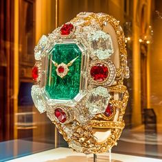 This striking second piece in the Dazzle Time collection radiates pure extravagance with a bold combination of emeralds, rubies, and diamonds, intricately crafted to resemble an ultra-luxurious watch. The oversized emerald centerpiece, surrounded by radiant diamonds and ruby accents, transforms the traditional idea of a timepiece into a dazzling work of art. The gold details and intricate settings evoke a sense of timeless grandeur, making this digital creation a stunning celebration of opulence. Welcome to my high-concept art for the wall, shelf, Digital Picture frame, or computer desktop wallpaper.  Art Description: Imperial Jewel commands attention with its resplendent emerald face, reminiscent of the grand treasures of empires past. The immense central emerald is framed by flawless dia Elegant Green Watch As A Gift, Elegant Green Watch For Gift, Diamond Watch With 17 Jewels As Gift, Luxury Jeweled Diamond Jewelry, Luxury Jeweled Emerald Jewelry, Luxury Diamond Watch With 17 Jewels As Gift, Luxury Green Diamond Watch For Formal Occasions, Green Luxury Diamond Watch For Formal Occasions, Elegant Green Diamond Watch For Formal Occasions