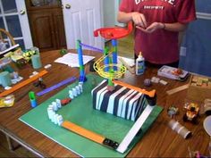 a young boy is making a model with construction materials on the table in front of him