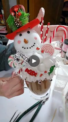 a cupcake decorated like a snowman with candy canes in it and decorations on top