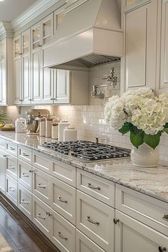 a kitchen with white cabinets and marble counter tops