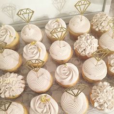 there are many cupcakes with white frosting on the top and gold decorations on the bottom