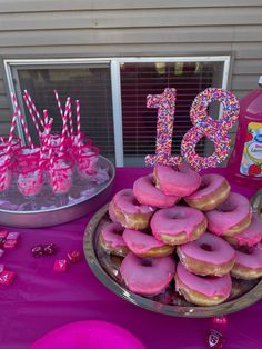 a table topped with lots of donuts covered in pink frosting and sprinkles