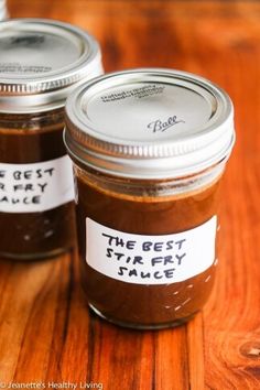 three jars with labels on them sitting on a wooden table, one labeled the best sticky sauce