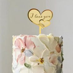 a wedding cake decorated with flowers and a wooden i love you sign on top that says i love you