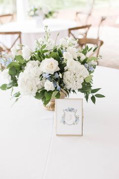 a vase filled with white and blue flowers on top of a table next to chairs