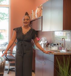 a woman standing next to a sink in a kitchen