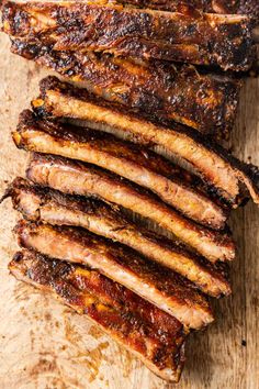 slices of barbecue ribs sitting on top of a cutting board