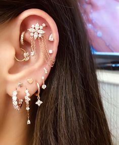 a close up of a person wearing ear piercings with flowers and leaves on them