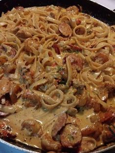 a skillet filled with pasta and meat covered in sauce