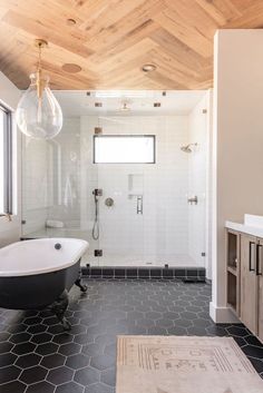 a bathroom with black and white tile flooring and wood paneled ceiling above the bathtub