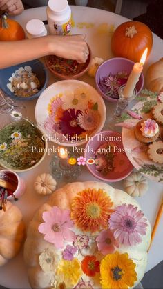 a table topped with plates and bowls filled with different types of flowers next to candles