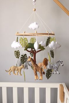 a baby crib with stuffed animals hanging from it's sides and a mobile in the shape of a tree