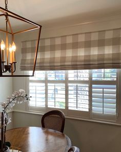 a dining room table and chairs in front of a window with blinds on the windowsill