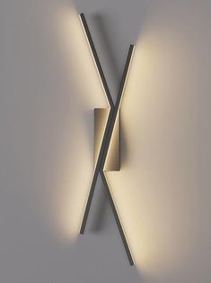 a modern light fixture with two lights on it's side and the wall behind it