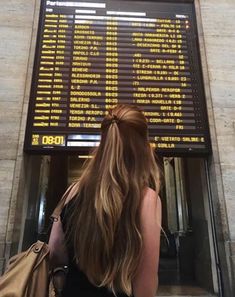 a woman is standing in front of an airport sign with her back to the camera