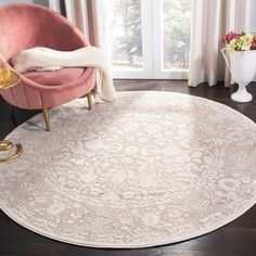 a round rug with an ornate design on the floor in front of a large window