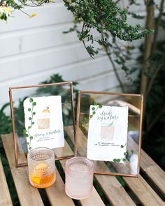 two glass coasters sitting on top of a wooden table next to a cup filled with liquid