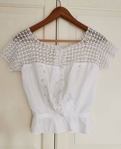 a white blouse hanging on a wooden hanger