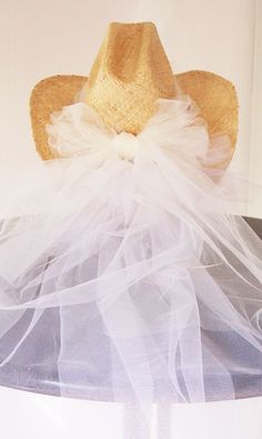 a straw hat on top of a white table with tulle around the brim