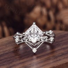 a princess cut diamond ring on top of a wooden table