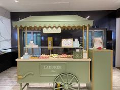 a green cart filled with lots of food on top of a tiled floor next to a wall