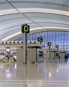 an airport terminal with two signs and people walking through the walkways in front of them