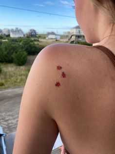 the back of a woman's shoulder with small red flowers on her left arm