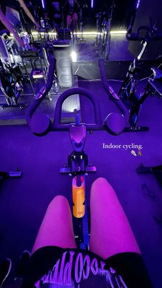 a person is sitting on a bike in the middle of a room with purple lighting