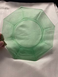 a person holding a green plastic plate on top of a white sheet