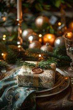 Beautifully wrapped gift with gold ribbon on a festive holiday table setting with candles and pine branches. Elegant Christmas Table, Colorful Ornaments, Christmas Table Decoration, Festive Tablescape, Gingerbread House Decorations, Clear Vase, Sophisticated Decor, Rustic Centerpieces, Thanksgiving Table Settings