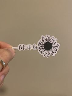 a person holding a stick with the word eat at home written on it and a sunflower