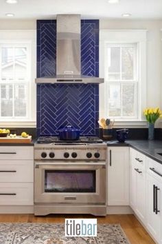 a kitchen with white cabinets and blue backsplash