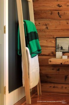 a towel rack in the corner of a room with wood paneling on the walls