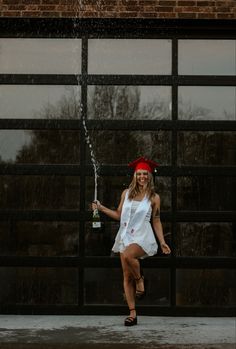 a woman in a white dress is spraying water on her head with a red bandana